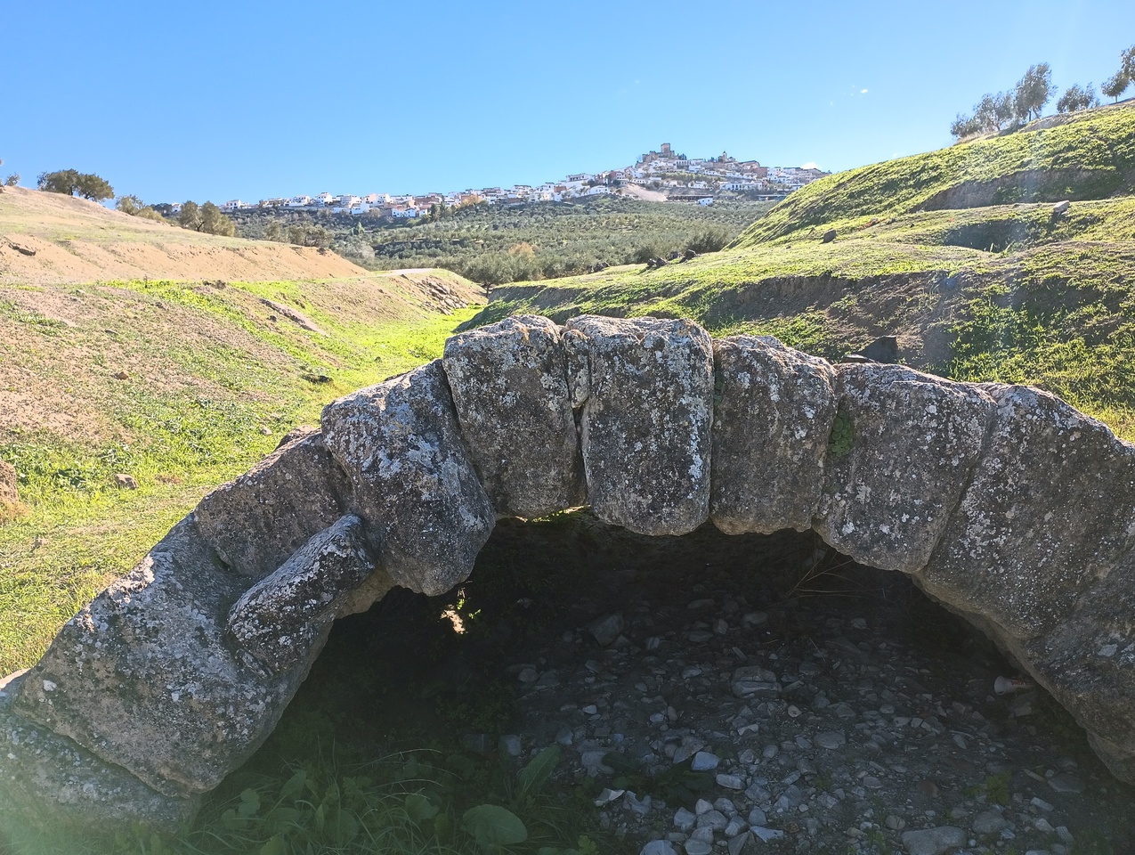 Small Roman bridge with Espejo and its hilltop castle in the background.