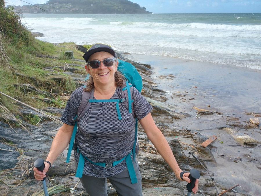 Woman with hiking poles on a beach.