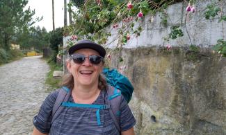 Woman in front of wall with hanging fuschias.